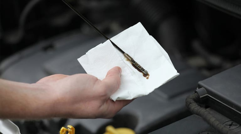 a mechanic testing the oil of a car