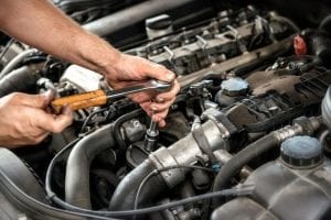 man using socket wrench for engine repair in coconut creek